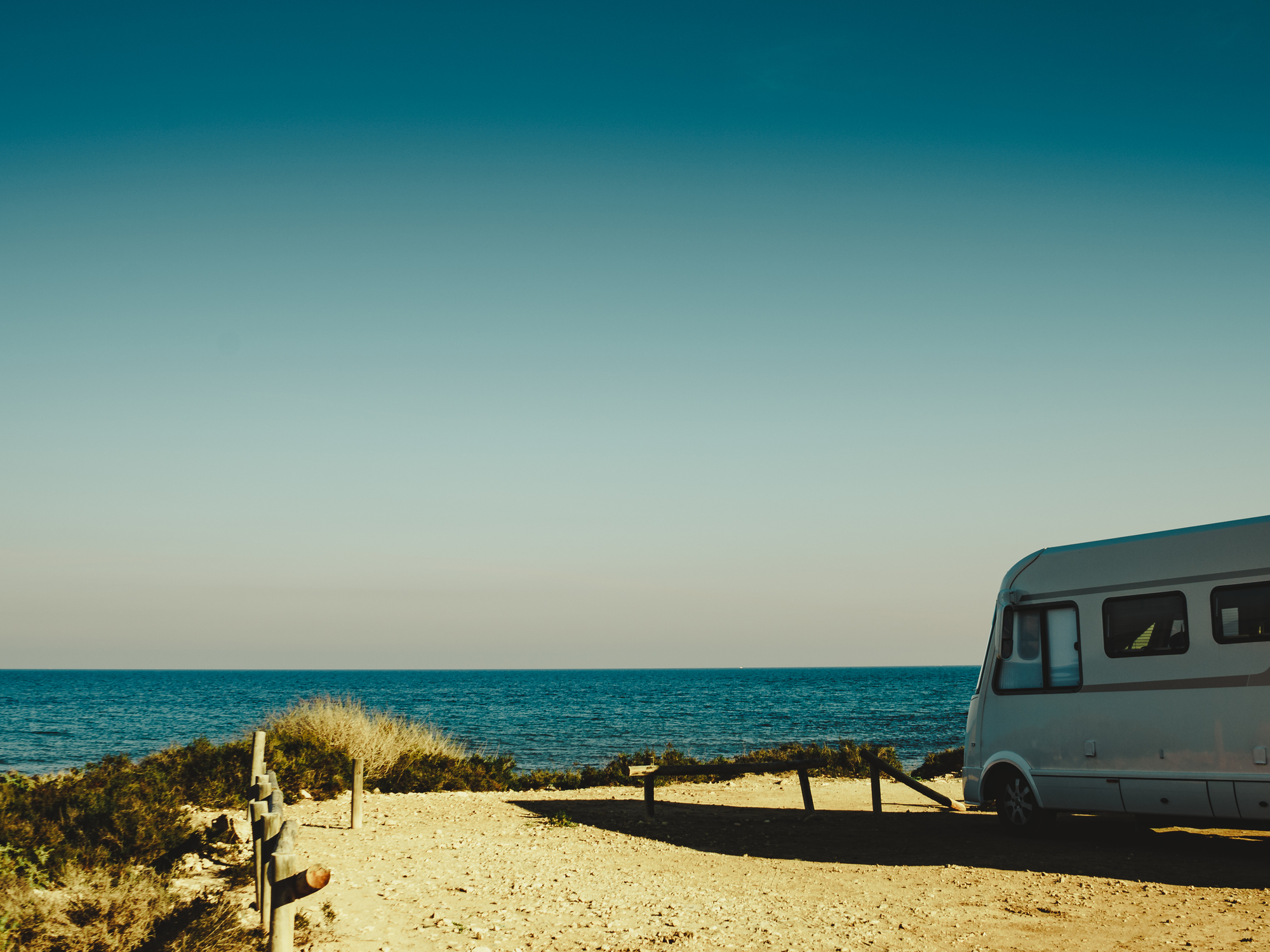Camper, recreational vehicle on mediterranean coast in Spain. Camping on nature beach. Holidays and travel in motor home.